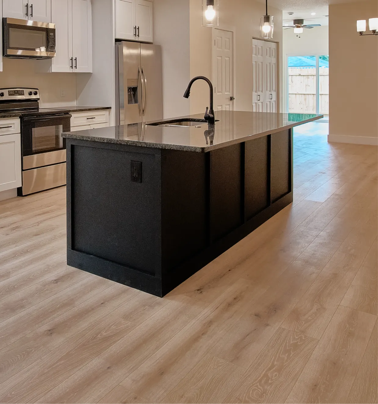 Remodeled open kitchen with a dark island, stone countertop and stainless steel appliances
