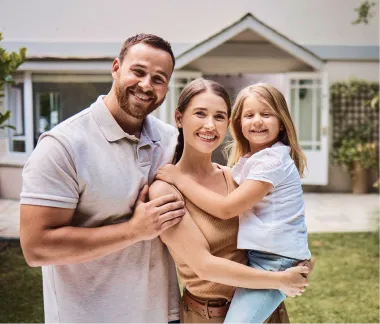 Smiling family standing in front of their home