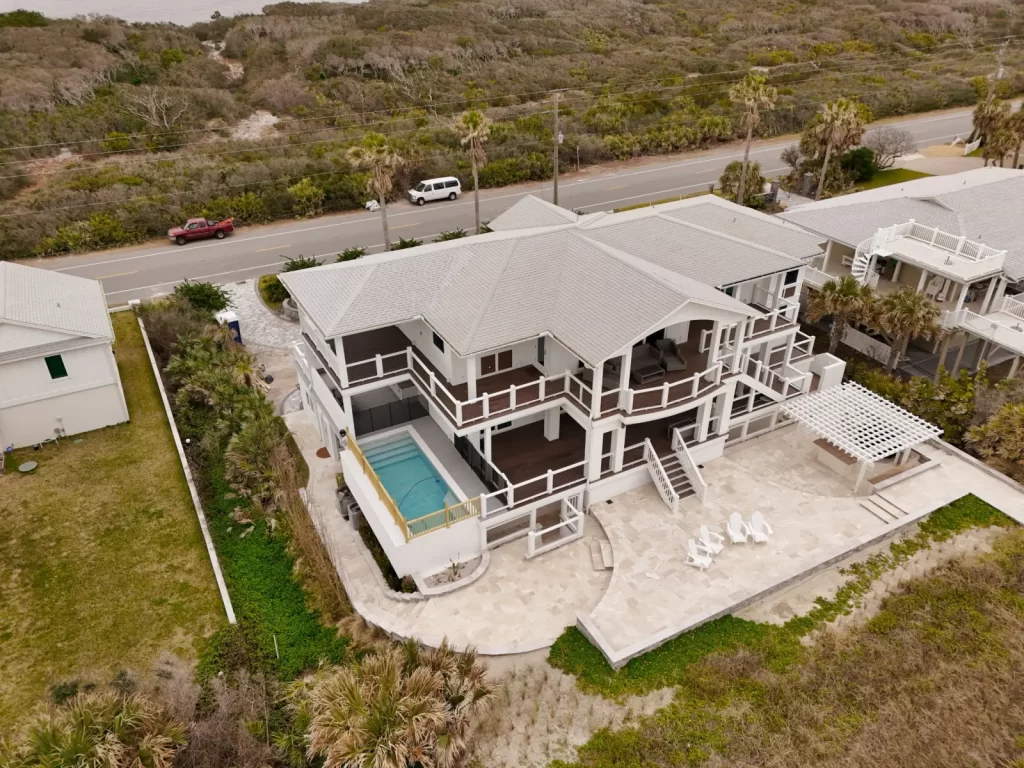 Aerial view of a beachfront home with elevated pool and travertine patio built by Artegiano Contracting