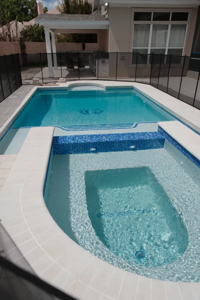 Custom pool with raised spa and blue glass tile in Jacksonville, FL by Artegiano Contracting